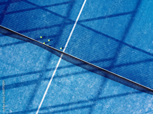 aerial top image of five balls near the net on a blue artificial grass paddle tennis court