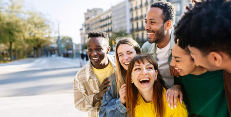 Young group of happy college students having fun together outside. Millennial diverse friends hanging out enjoying travel vacation in city street. Copy space for text.