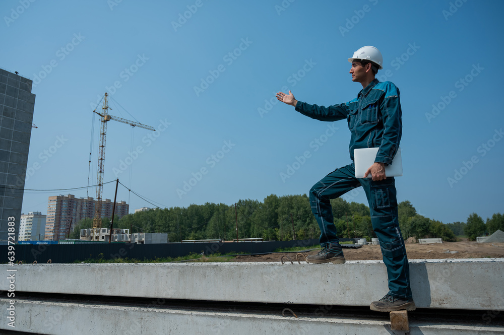 Caucasian male builder in hardhat holding laptop at construction site. Caucasian male builder in hardhat holding laptop at construction site.