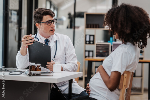 Male gynecologist doctor checking african american pregnant woman, Gynecology Consultation concept, examining belly stethoscope, obstetrician OB doctor special training in women health and pregnancy