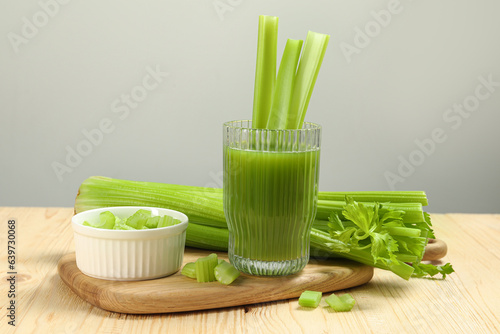 Glass of celery juice and fresh vegetables on wooden table