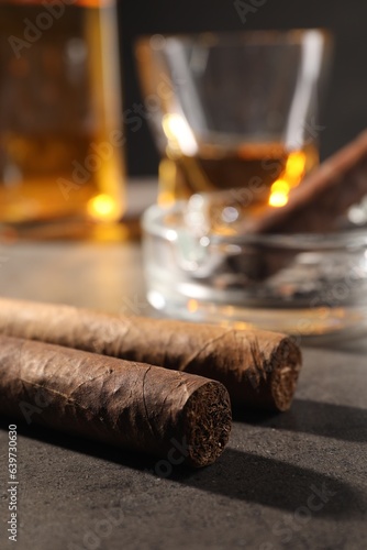 Cigars, ashtray and whiskey on grey table, closeup