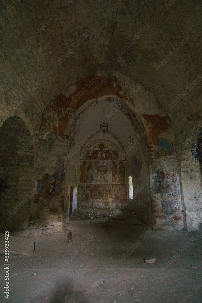 Inside of abandoned church of ghost town Janovas in the pyrenees mountains with old painting on the wall, Huesca, Aragon, Spain