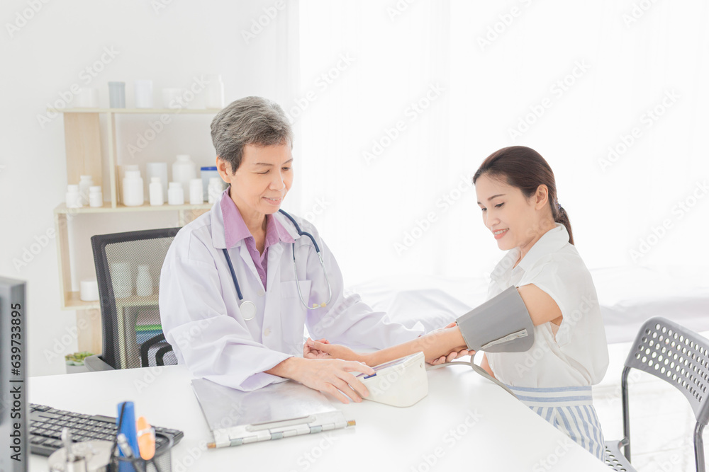 Asian female doctor talk with female patient about blood pressure, adult health check up, hypertension screening in hospital Asian female doctor talk with female patient about blood pressure, adult health check up, hypertension screening in hospital