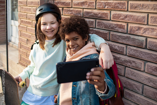 Young boy and girl taking a selfie with a smart phone on a sidewalk in the city after skipping school photo