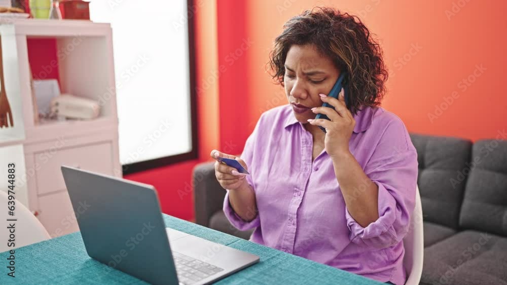 Young beautiful latin woman shopping with laptop and credit card talking on smartphone at dinning room Young beautiful latin woman shopping with laptop and credit card talking on smartphone at dinning room