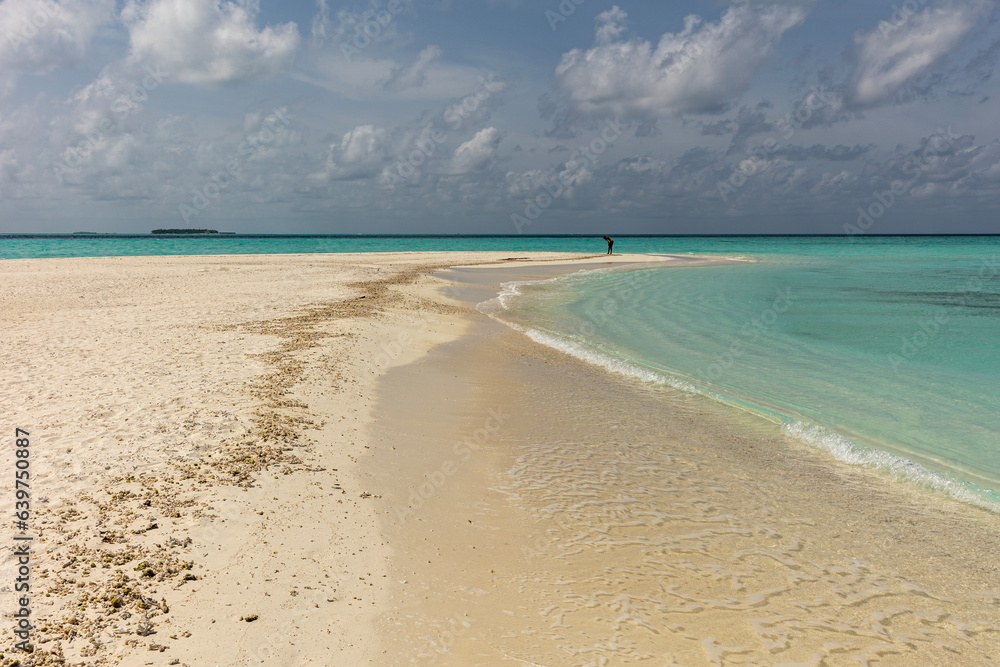 Coral sand beach on sunny day with blue cloudy sky and calm waves