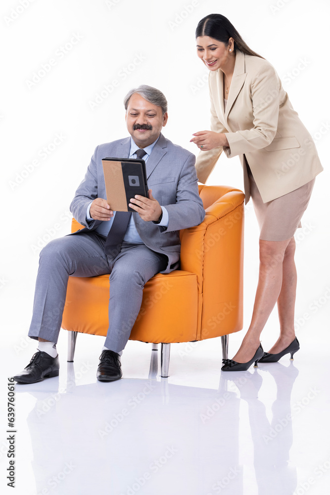 Two businesspeople working together on a digital tablet against white background.