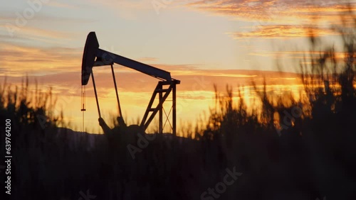 Silhouette of oil pump working at dawn in Vernal, Utah countryside, slow motion