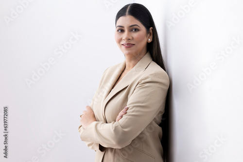 Portrait of smiling businesswoman dressed in formalwear standing confidently against white background