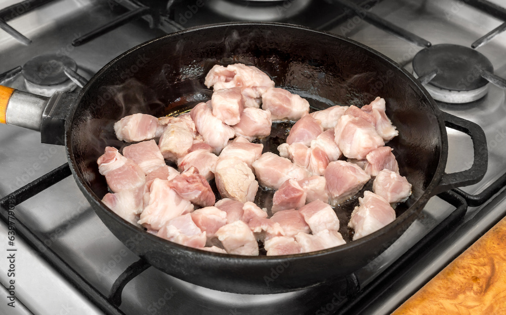Frying pan with cutted meat on cookstove. Frying pan with cutted meat on cookstove.