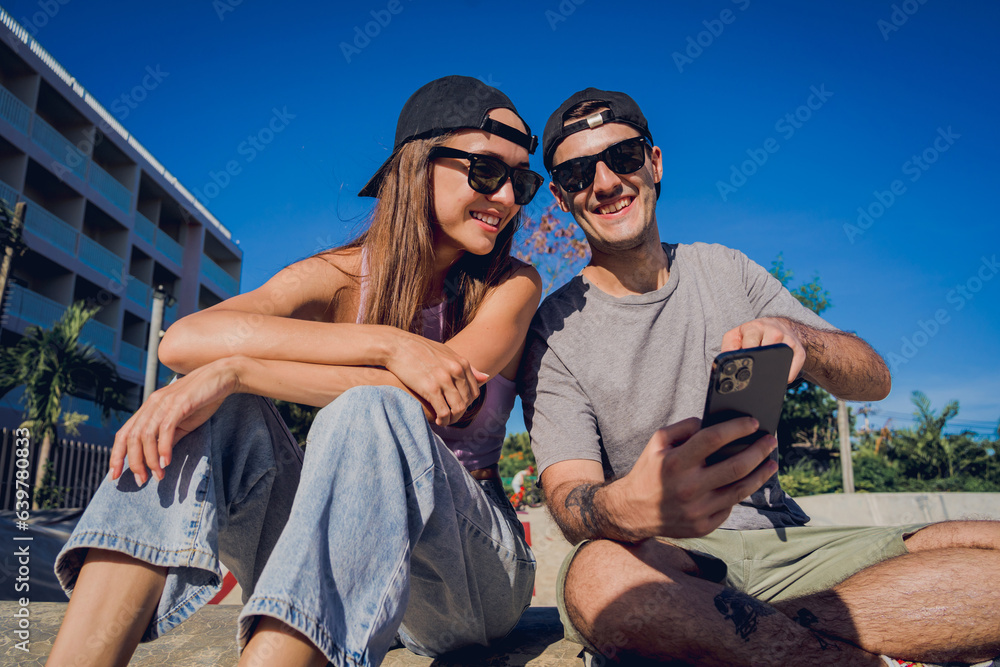 Young happy couple with skateboards taking selfie at the skatepark