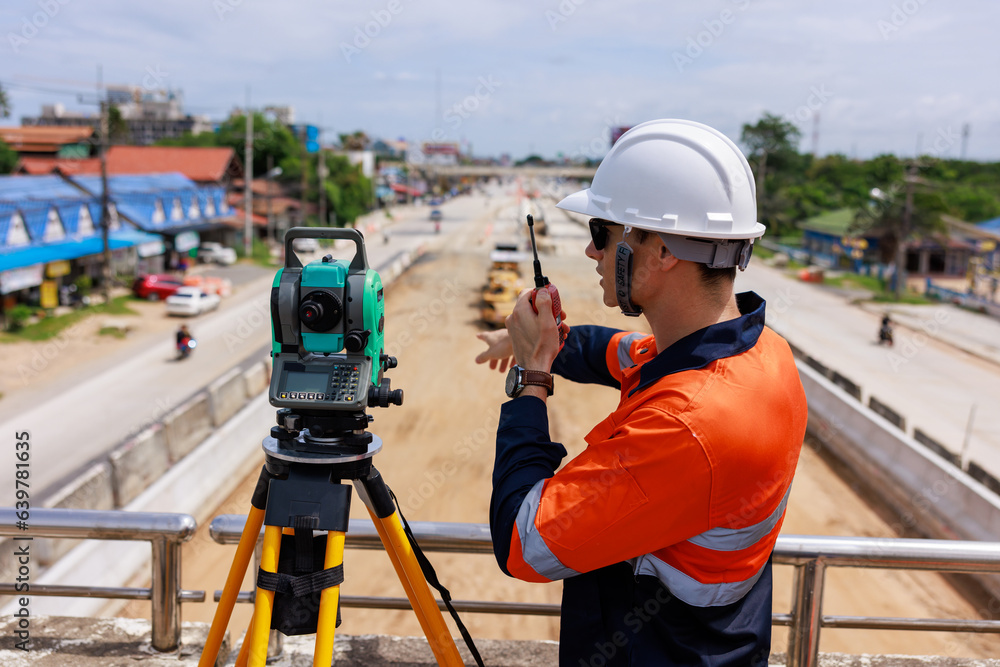 Surveyor engineer wearing safety uniform and helmet with equipment theodolite to measurement positioning on the construction site of the road Surveyor engineer wearing safety uniform and helmet with equipment theodolite to measurement positioning on the construction site of the road