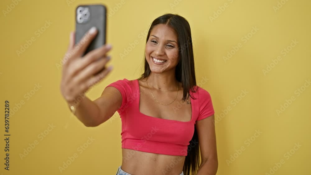 Young latin woman smiling confident having video call over isolated yellow background Young latin woman smiling confident having video call over isolated yellow background