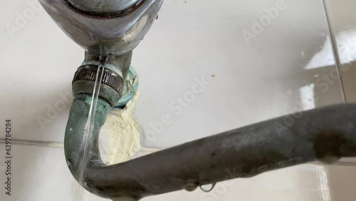 Water leaking from pipe on white wall at home kitchen sink close up view daytime. Home appliance repair and fix concept