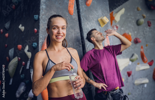 A strong couple of climbers against an artificial wall with colorful grips and ropes. © romaset