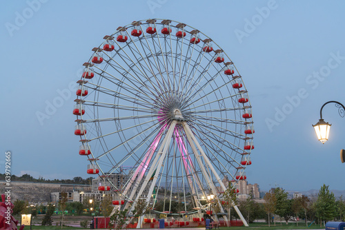 Colorful Ferris wheel of the amusement park in the blue sky and cloud background. Multicolor Ferries wheel on blue sky background
