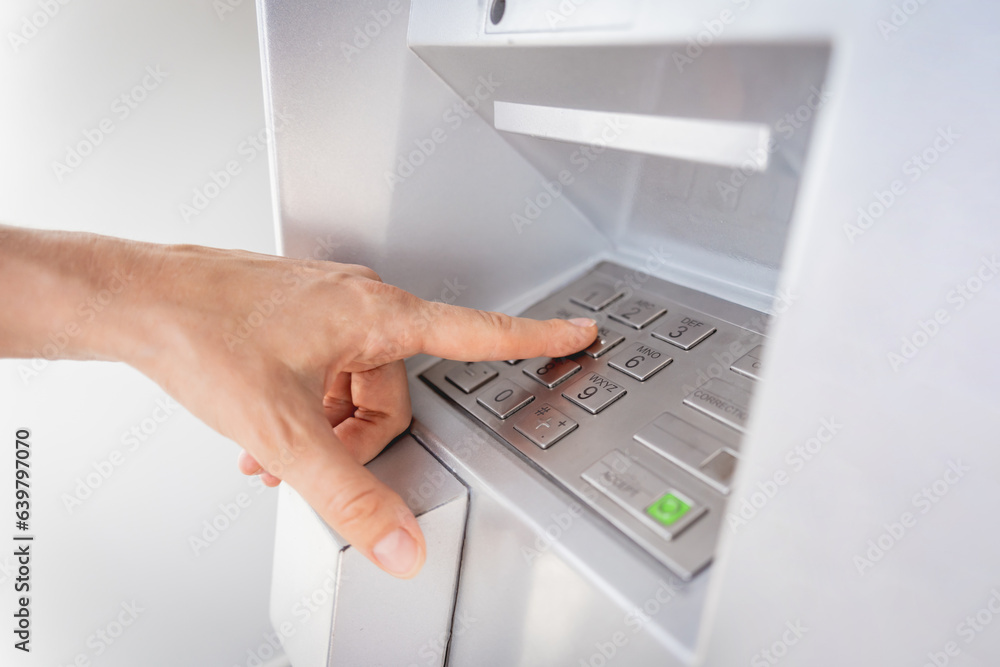 Young woman using the card for withdrawing the cash in the ATM
