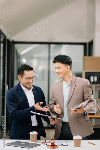 Two Asian businessman and man discuss investment project working and planning strategy with tablet laptop computer in modern office..