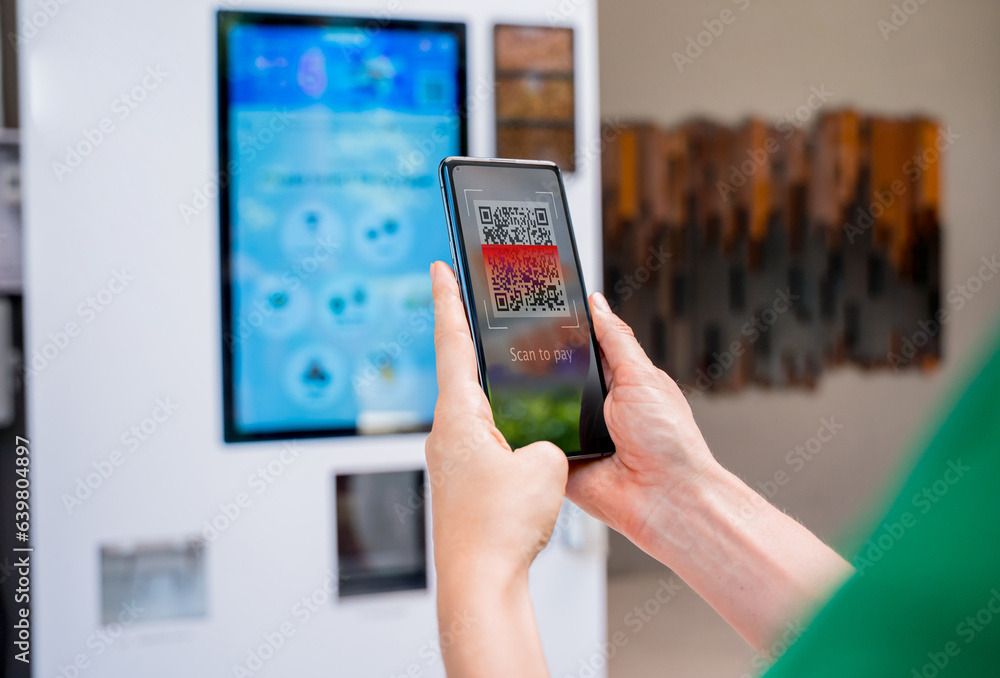 Young woman paying for coffee at vending machine using contactless method of payment Young woman paying for coffee at vending machine using contactless method of payment