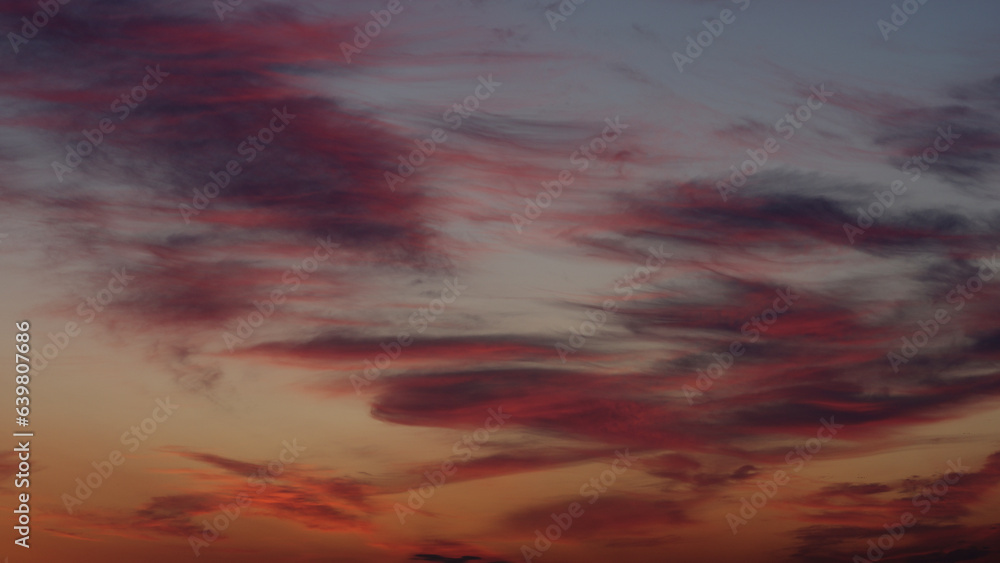 Colorful clouds on summer sunset sky with plane landing