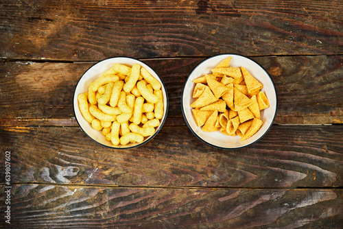 Peanut flips and cone corn chips in a ceramic bowl on wood table . Also known as Bamba, peanut puffs or snips, is a puffed, peanut-flavored corn snack