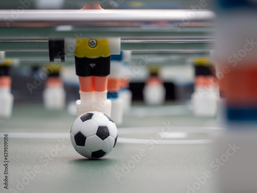 A close-up of some players and a soccer ball on a foosball table. Board game football.