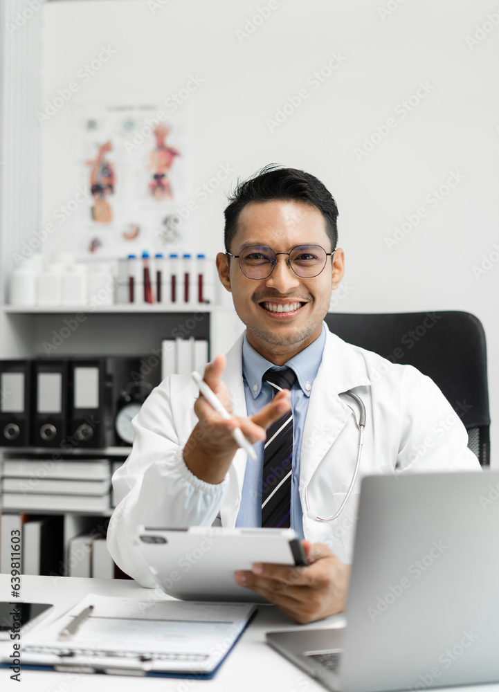 Male doctor sitting at a desk, looking at the camera. Male doctor sitting at a desk, looking at the camera.