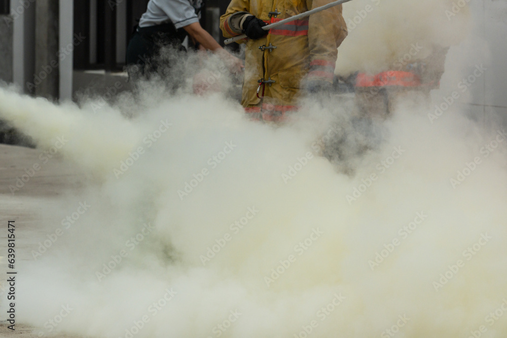Fototapeta premium Showing how to use a fire extinguisher on a training fire for employees industry.Firefighter working on the fire site.Fire fighter concept.