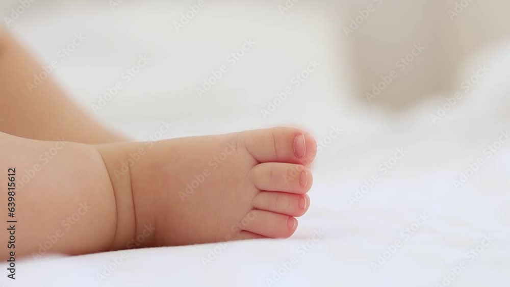 baby's small feet on a white bed, a place for text, a close-up of a little baby's feet baby's small feet on a white bed, a place for text, a close-up of a little baby's feet