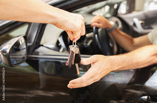 Valet parking worker giving key to man sitting in car photo