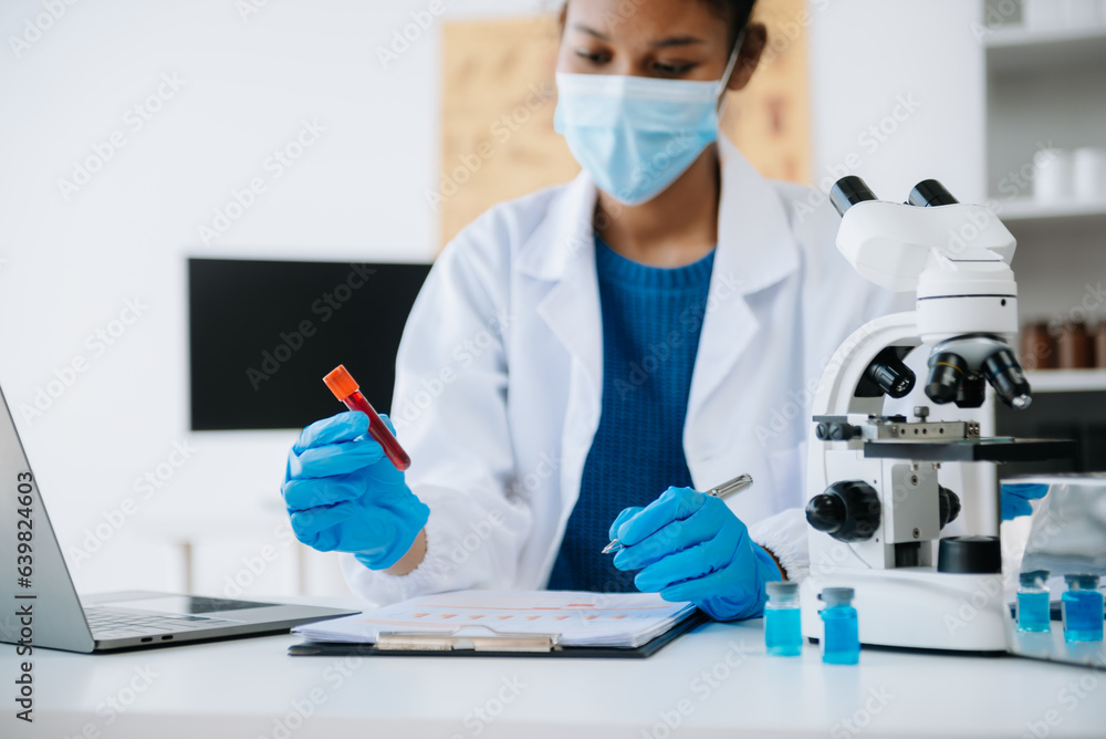 .Young scientists conducting research investigations in a medical laboratory, a researcher in the foreground is using a microscope in laboratory for medicine. .Young scientists conducting research investigations in a medical laboratory, a researcher in the foreground is using a microscope in laboratory for medicine.