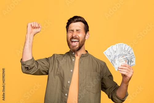 Lucky winner. Overjoyed middle aged man holding money cash in hands, euphoric male celebrating big profit