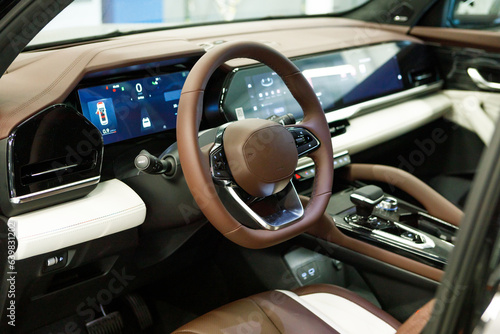 empty interior of modern premium car with three touch displays. white and brown interior, driver's seat © AvokadoStudio