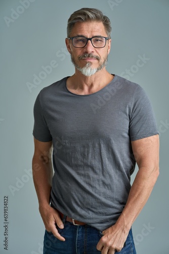Portrait of happy casual older bearded man with glasses and gray hair smiling, Mid adult, mature age guy standing, isolated on gray background.