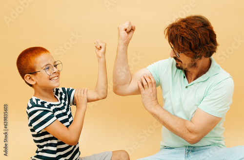 Happy child and his father playing together. Father and son compete in arm wrestling