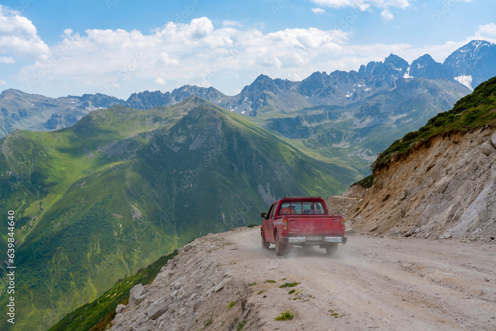 A red pickup truck driving on dirt roads on high plateau roads A red pickup truck driving on dirt roads on high plateau roads