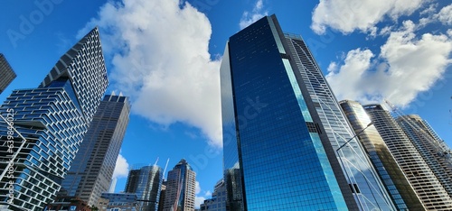 Downtown, skyscrapers in Sydney, below view. Huge buildings, highrise towers, blue cloudy sky.