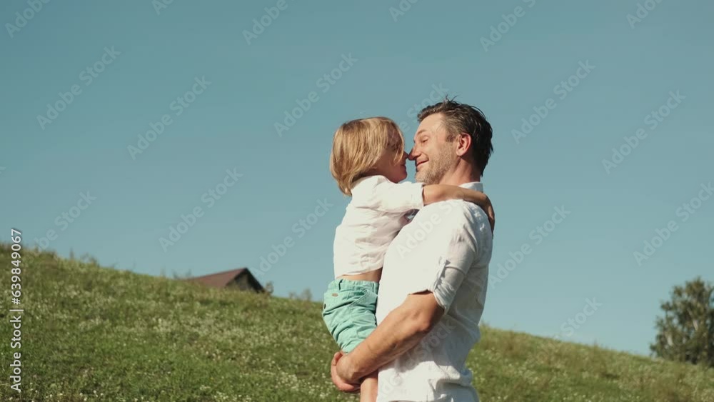 Father plays with his son holding him in his arms on the lawn. Father plays with his son holding him in his arms on the lawn.