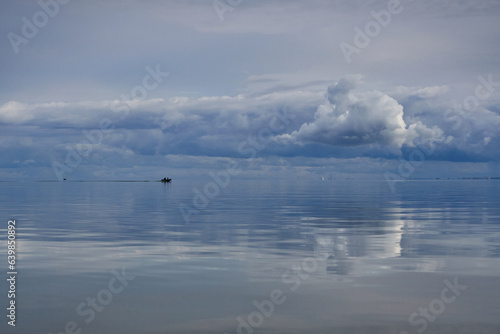The surface of the sea like a mirror reflects the sky with clouds.
