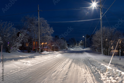 Winter street lit by lanterns in the polar village © Alexander