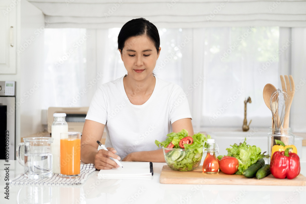 Diet, Dieting asian woman write diet plan right nutrition on table with fresh vegetables salad, is different food ingredients in the green. Nutritionist of healthy, nutrition of weight loss. Diet, Dieting asian woman write diet plan right nutrition on table with fresh vegetables salad, is different food ingredients in the green. Nutritionist of healthy, nutrition of weight loss.