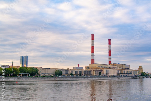 Moscow, Russia - August 12, 2022 : Thermal power plant in Moscow on the waterfront and a motor ship taking a boat trip