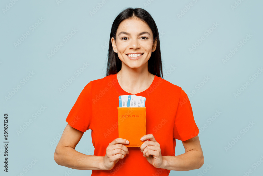 Traveler young fun latin woman wear red casual clothes hold passport ticket isolated on plain blue background. Tourist travel abroad in free spare time rest getaway. Air flight trip journey concept. Traveler young fun latin woman wear red casual clothes hold passport ticket isolated on plain blue background. Tourist travel abroad in free spare time rest getaway. Air flight trip journey concept.