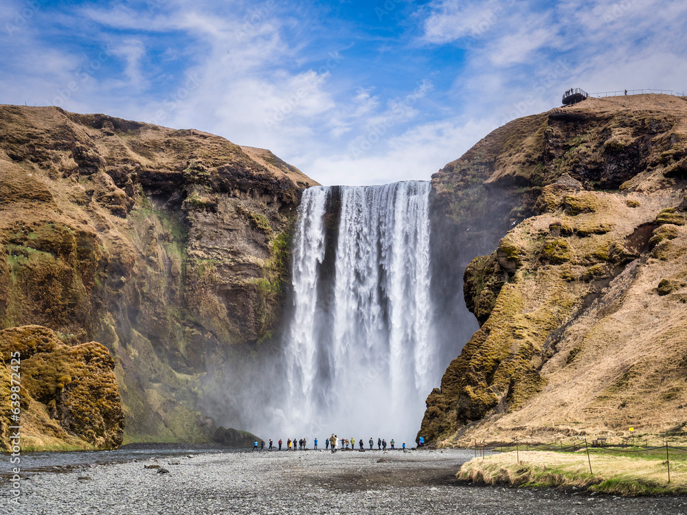 Visitors at the foot of Skogafoss, a famous waterfall in South Iceland. Visitors at the foot of Skogafoss, a famous waterfall in South Iceland.