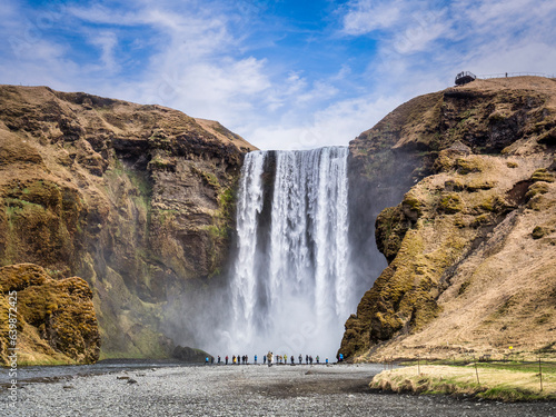 Visitors at the foot of Skogafoss, a famous waterfall in South Iceland.