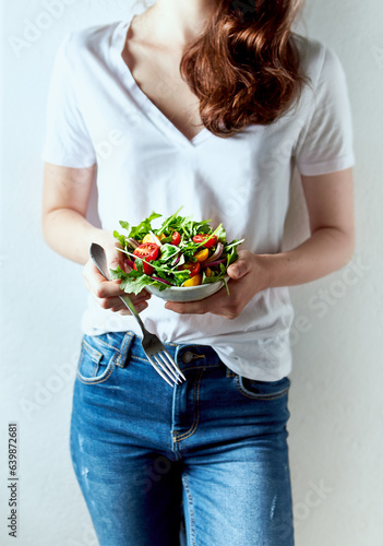 Young woman holding a bowl of healthy arugula and cherry tomato salad. Healthy lifestyle concept