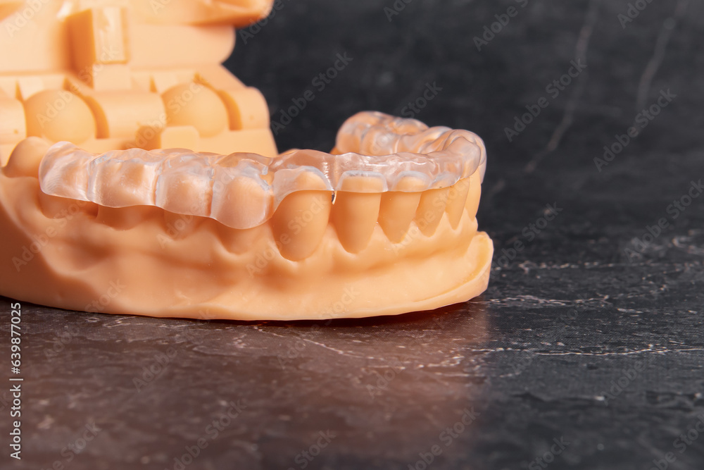 Aligners for teeth alignment on orange plastic jaw model. Lower jaw