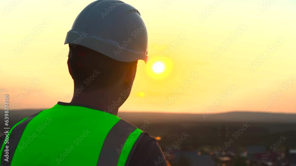 Silhouette of a man in a work helmet against the background of the setting sun. Silhouette of a man in a work helmet against the background of the setting sun.