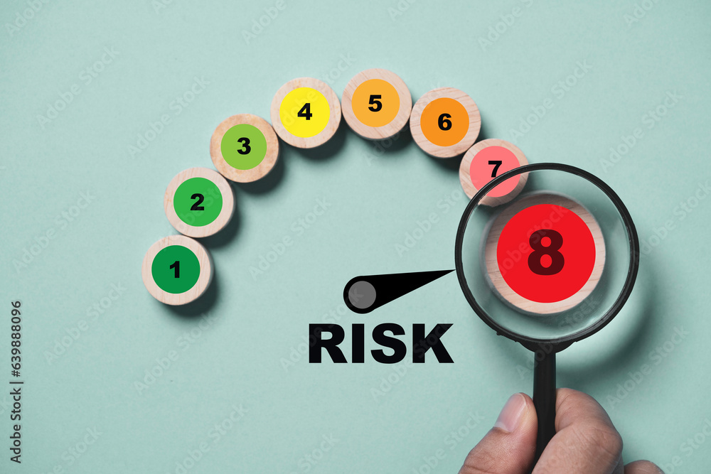Hand holding magnifier glass with risk level indicator rating print screen wooden cube block since low to high on blue background for focus risk Assess management of investment and working concept. Hand holding magnifier glass with risk level indicator rating print screen wooden cube block since low to high on blue background for focus risk Assess management of investment and working concept.